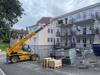 Teleskoptruck lufter upp material till balkong av nybyggt lägenhetshus